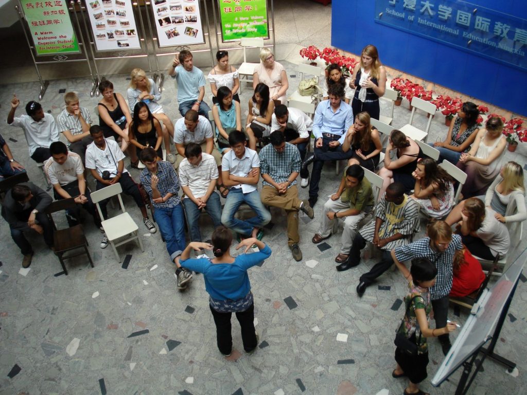 Students gathered in circle interacting with a teacher.