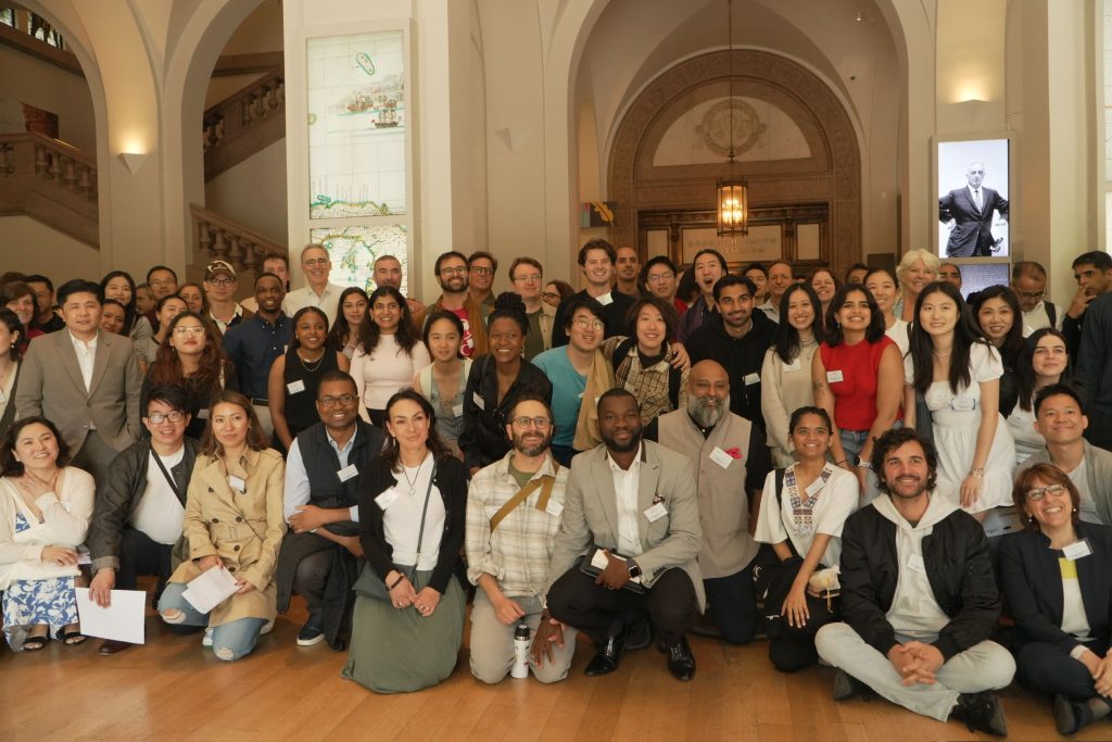 Photo of the attendees at an Impact for Innovation forum. A large group of people posing for a photo in a grand hallway
