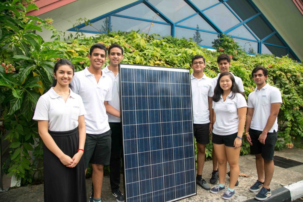 Students standing around a solar panel.