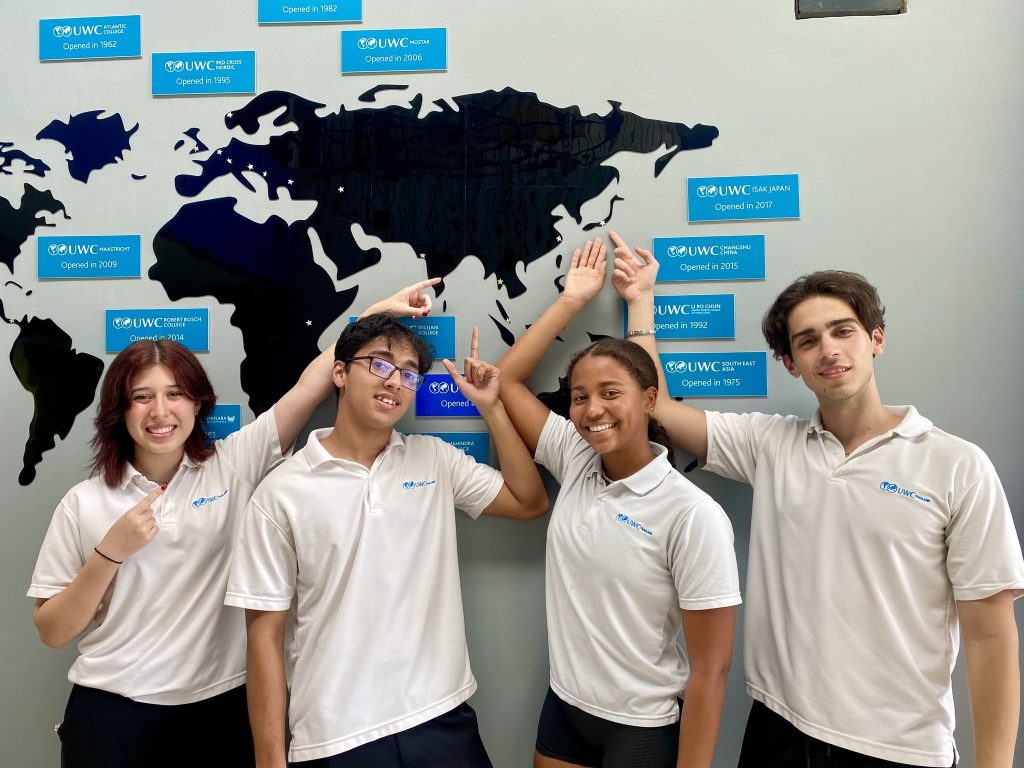 Students pointing out the 18 colleges around the world on a map